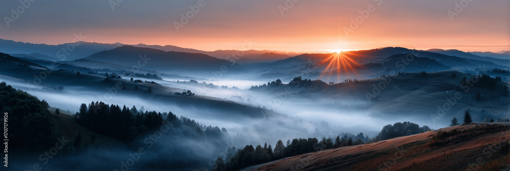 Obraz premium The sun is setting over a mountain range, casting a warm glow over the landscape