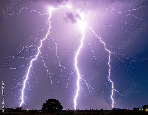 Eerie lightning strikes illuminating a field at night, with striking violet and blue tones from the powerful electrical discharge