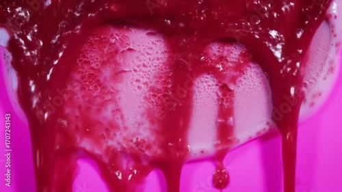 Close up of red liquid dripping onto a white surface.