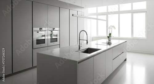A modern, minimalist kitchen with a large island, integrated ovens, and abundant natural light from a large window.