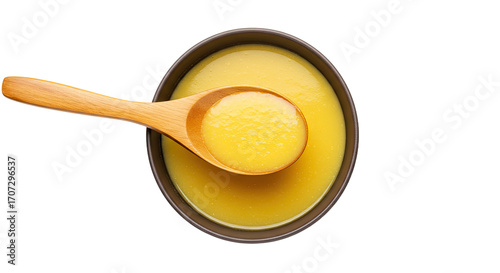 Golden yellow liquid in bowl with wooden spoon.