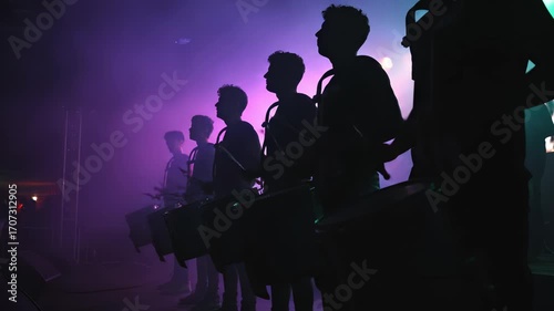Group of drummers silhouetted against vibrant blue and purple lights, creating a dynamic rhythm in a lively performance, showcasing the energy and excitement of live music