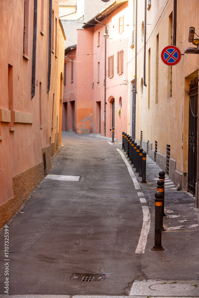 Obraz premium An enchanting, narrow European alleyway, flanked by traditional buildings with warm-toned stucco and closed shutters, creating a feeling of classic, old-world urban life perfect for travel or architec