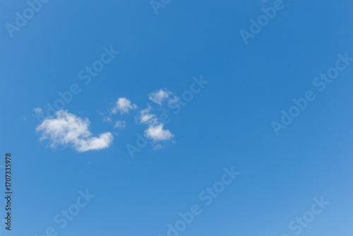 Minimal blue sky with small white clouds
