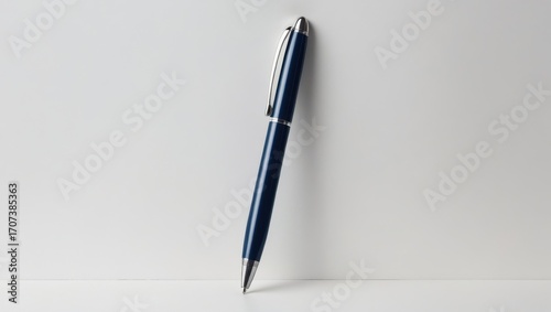 A navy blue ballpoint pen rests on a plain white surface, showcasing its sleek design.