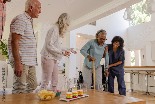 Senior friends enjoying time together at home with caregiver assisting