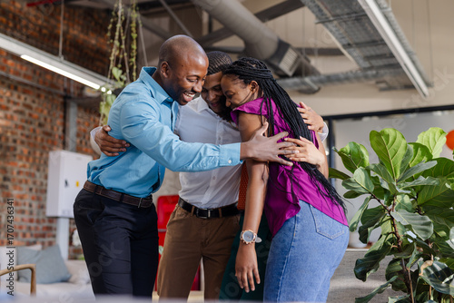 Colleagues in office hugging and celebrating success with joyful expressions