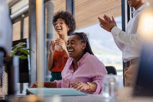 African American woman laughing with colleagues in office during successful meeting
