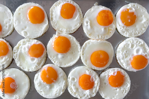 Fried egg arranged in a neat pattern on a baking tray in a bright kitchen setting during the morning hours