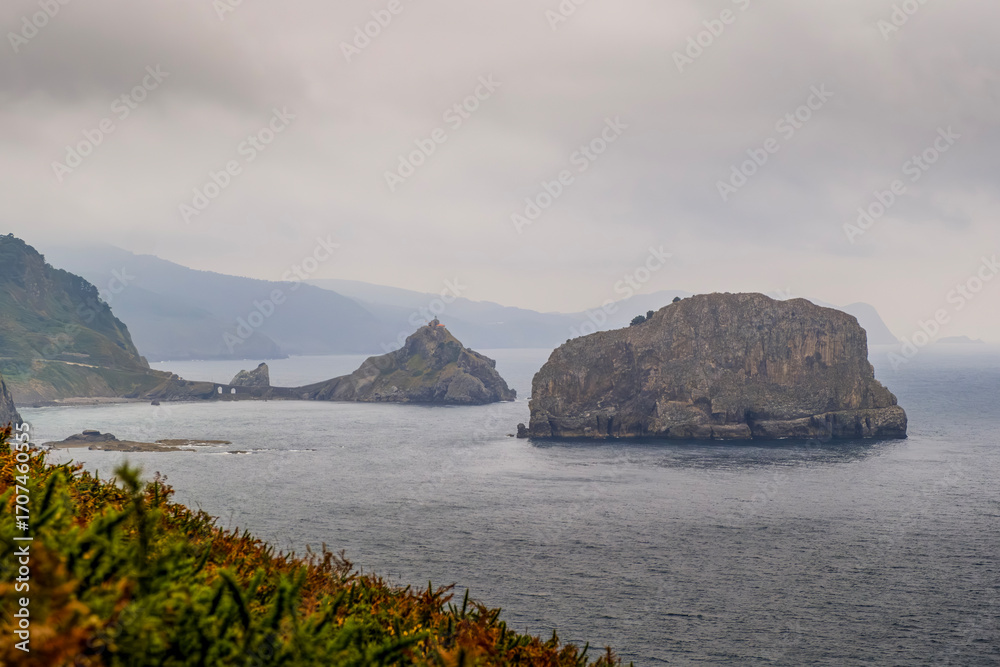 Naklejka premium San Juan De Gaztelugatxe View From Cape Machichaco Lighthouse Basque Coast. Rocky Outcrops, Atlantic Ocean, Game Of Thrones Location, Northern Spain