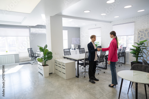 Caucasian man and woman greeting and shaking hands in office. 