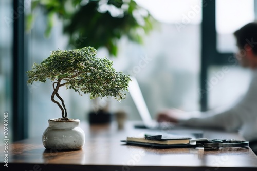 A minimalist desk with a single bonsai tree beside a laptop. A worker typing slowly, enjoying the fresh scent of greenery. The mood feels serene, Generative AI
