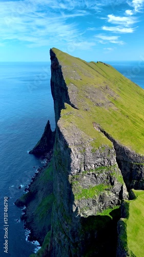 Explore breathtaking cliffs rising dramatically from the Atlantic Ocean in the Faroe Islands. Lush green landscapes contrast with the deep blue waters, Mylingur cliff hiking trail