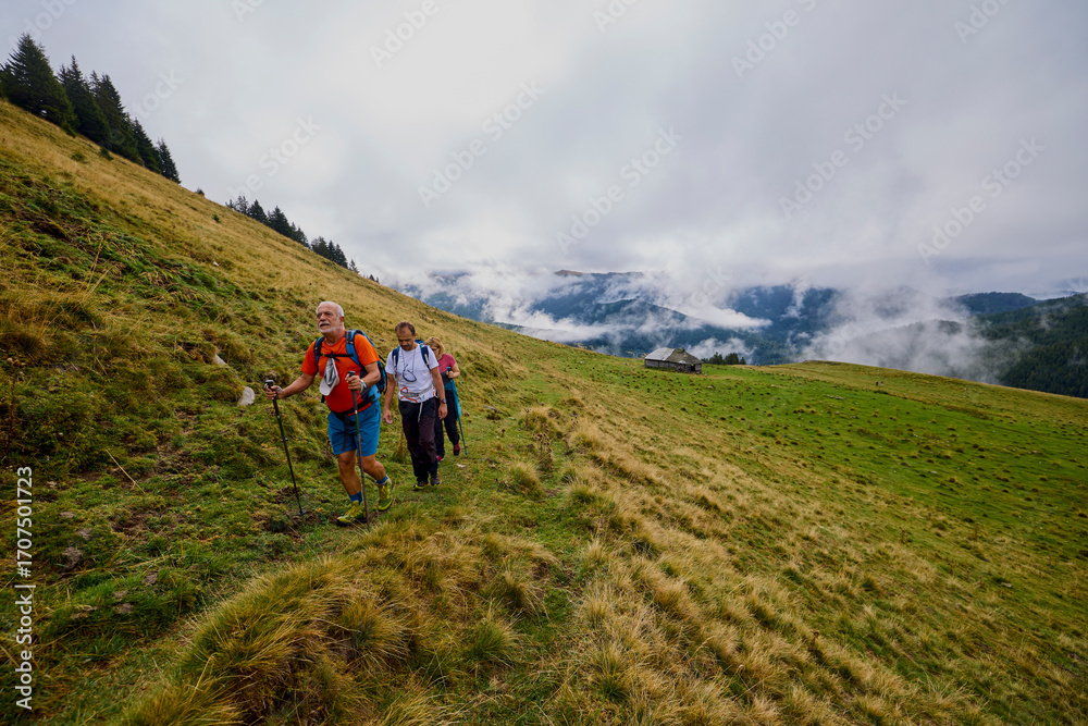 Obraz premium a couple with their grandfather walking in the mountains on a cloudy and foggy day.