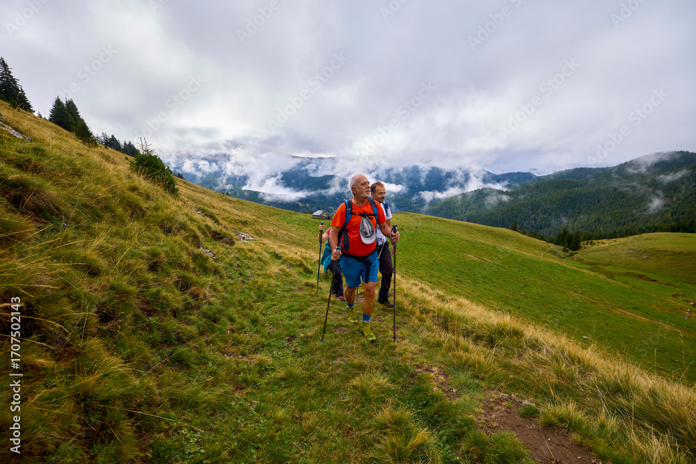 Obraz premium a couple with their grandfather walking in the mountains on a cloudy and foggy day.
