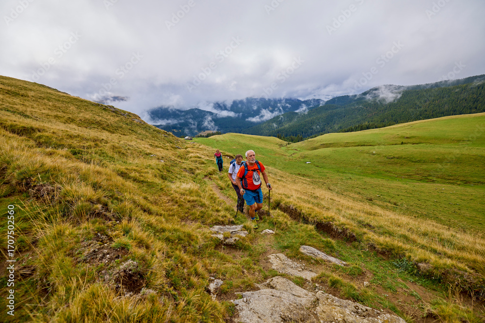 Fototapeta premium a couple with their grandfather walking in the mountains on a cloudy and foggy day.