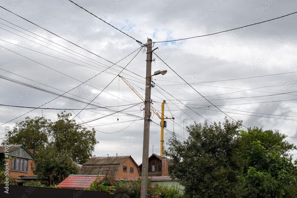Obraz premium Concrete electric pole with wires against gray sky
