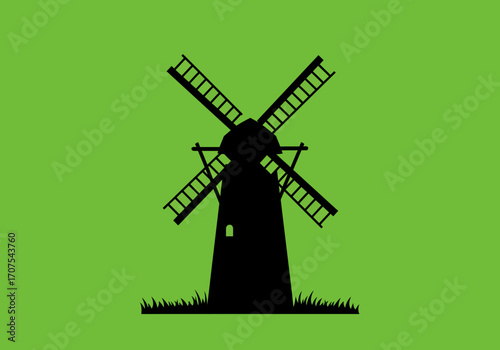 A silhouetted windmill with blades  grass against a green background