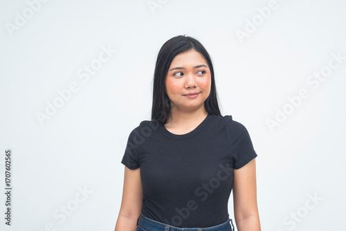 Konstfotografi A distracted young Asian woman in a half body shot glancing to the side with a soft smile, appearing lost in thought