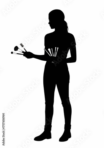 A makeup artist holding makeup brushes silhouette.