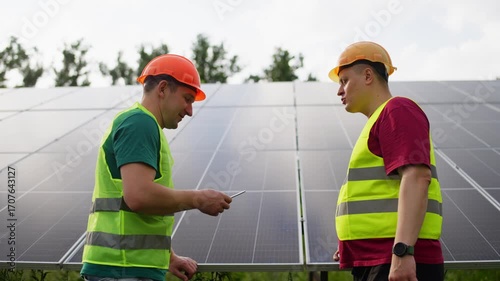 Professional engineers control and discuss the efficiency of solar panel electricity production renewable green energy technologies and modern environmental protection using tablet. 