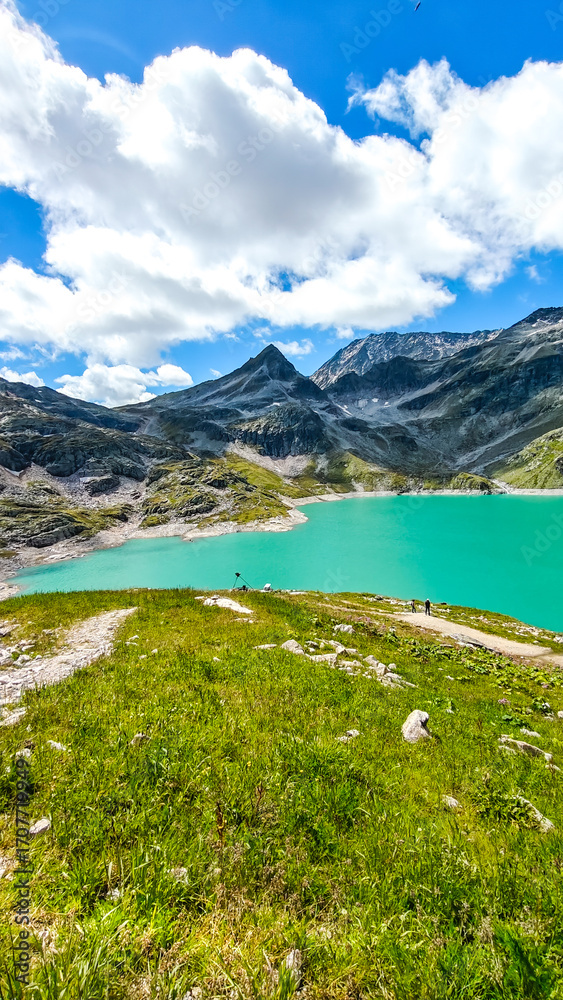 Fototapeta premium Austria, 08-2025 : wide shot of Weißsee lake, mountains and glaciers in background. People hiking in front.