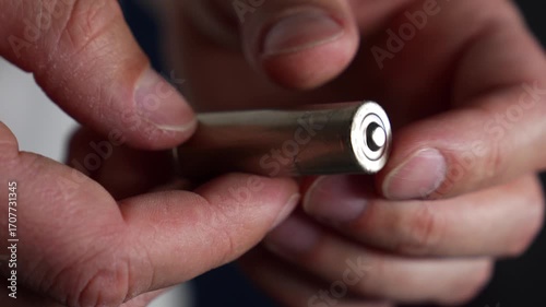 A close-up of a hand holding an AA battery.
Charging electric batteries.
Disposing of a metal AA battery after use.