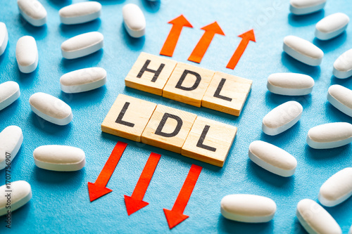 Concept of increasing HDL cholesterol and decreasing LDL cholesterol, terms composed with wooden alphabet and up and down arrows.