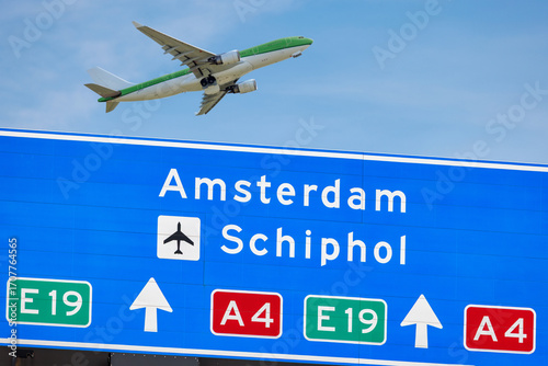 Photography Dutch highway route sign to Amsterdam and Schiphol airport with passenger airpla