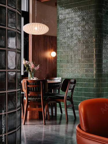 Cafe interior: wooden table and chairs near green tiled wall and glass window. Empty dining room, designed in mid-century modern style with lots of wooden elements, green tiles and glass blocks.