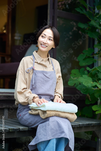 縁側に座る主婦　洗濯物をたたむエプロンの女性