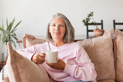 Portrait happy healthy middle aged woman sitting on comfortable couch at home