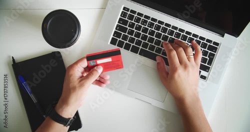 Man using laptop and holding credit card on desk with coffee cup and notebook. Concept of online shopping, ecommerce and digital payment.