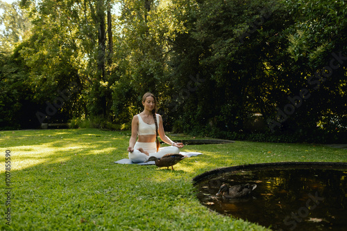 Woman practicing yoga and meditation in a public park, relaxed with closed eyes. Mindful meditation concept. Wellbeing. No focus blurred and noise effect. Part of the series