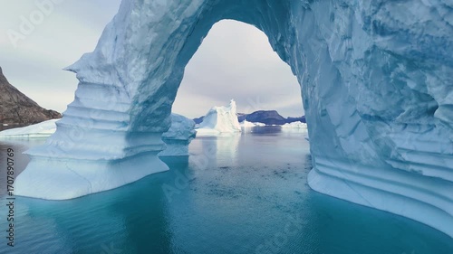 
Melting iceberg peacefully floats in the ocean. Ice floe reflecting in crystal sea, Greenland. Ecology, climate change global warming. An aerial perspective showcases the dramatic melting icebergs