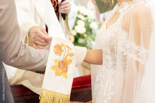 Close-up of priest’s stole placed over couple’s hands during wedding vow exchange ceremony in church, symbol of unity and blessing