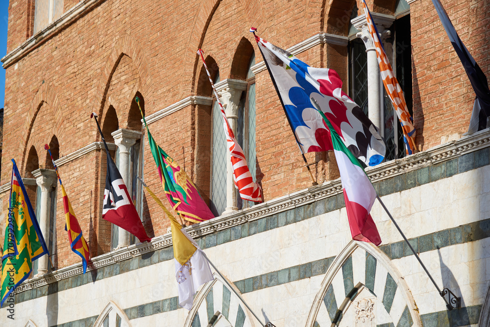 Obraz premium Group of flags waving on a facade in Siena, Tuscany, Italy.
