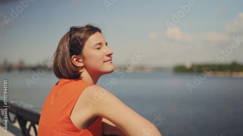 Beach holiday and freedom: cute young girl gazing at sea view near waterfront