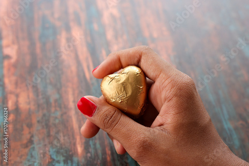 Gold plated chocolate heart shaped. Chocolate candy in the shape of heart covered in golden wrap. Valentines day concept