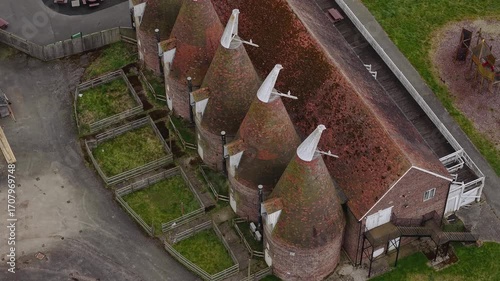 Aerial birdseye view over rows of Hop farm cylindrical kilning oast houses rooftops in Kent