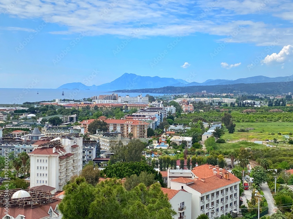 Fototapeta premium Panoramic view of Mediterranean coastal resort village with gardens and hotel in Camyuva, near Kemer, Antalya, Turkey. The Taurus Mountain Range.