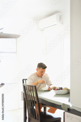 Man in His 30s Eating Muesli at the Kitchen Table During Morning Routine.