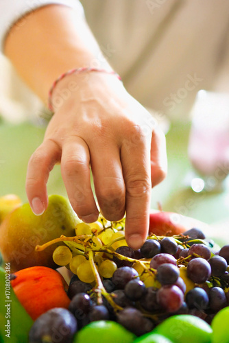 A man reaching for some grapes.