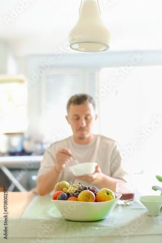 Man Chewing a Bite of Oats While Sitting an his Dinning Table.