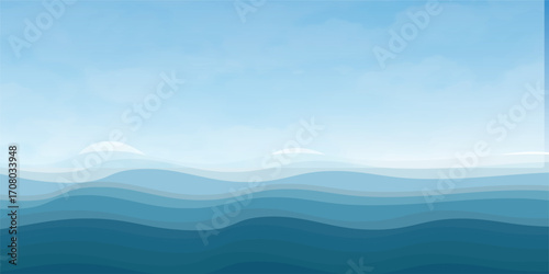 Blue sea waves with a misty mountain landscape at sunrise and a sky full of clouds