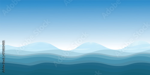 Blue sea waves with a misty mountain landscape at sunrise and a sky full of clouds