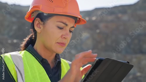 Female engineer using tablet at quarry site for data analysis and inspection
