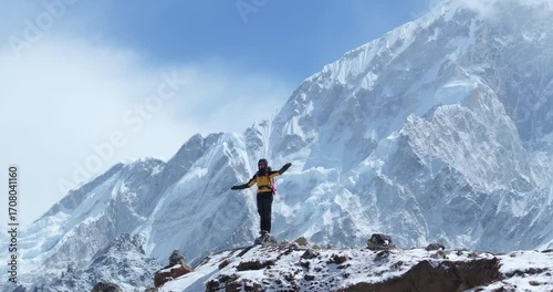 Drone shot of a tourist standing tall amidst Lhotse peak on the Everest Base Camp trek in Khumbu, Nepal. A 360° aerial reveals snow-capped Himalayas, breathtaking scenery, and high-altitude adventure