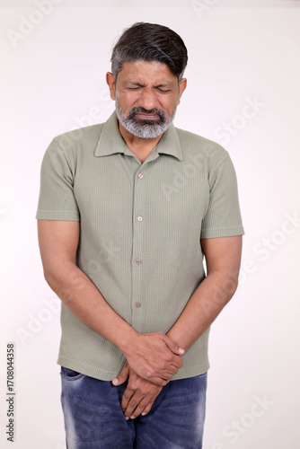Indian middle aged pain man patient hands holding his crotch with prostate problems, feel itchy, sore and swollen. He is suffering from health issues and urinary incontinence with a bladder infection