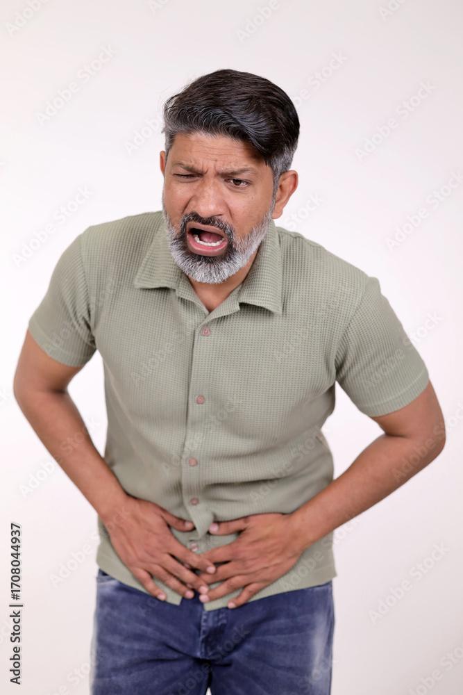 Fototapeta premium Indian man feeling pain torching on stomachache isolated on white background in studio. Middle aged man hand on stomach because pain disease feeling unwell. With copy space. Food Poising